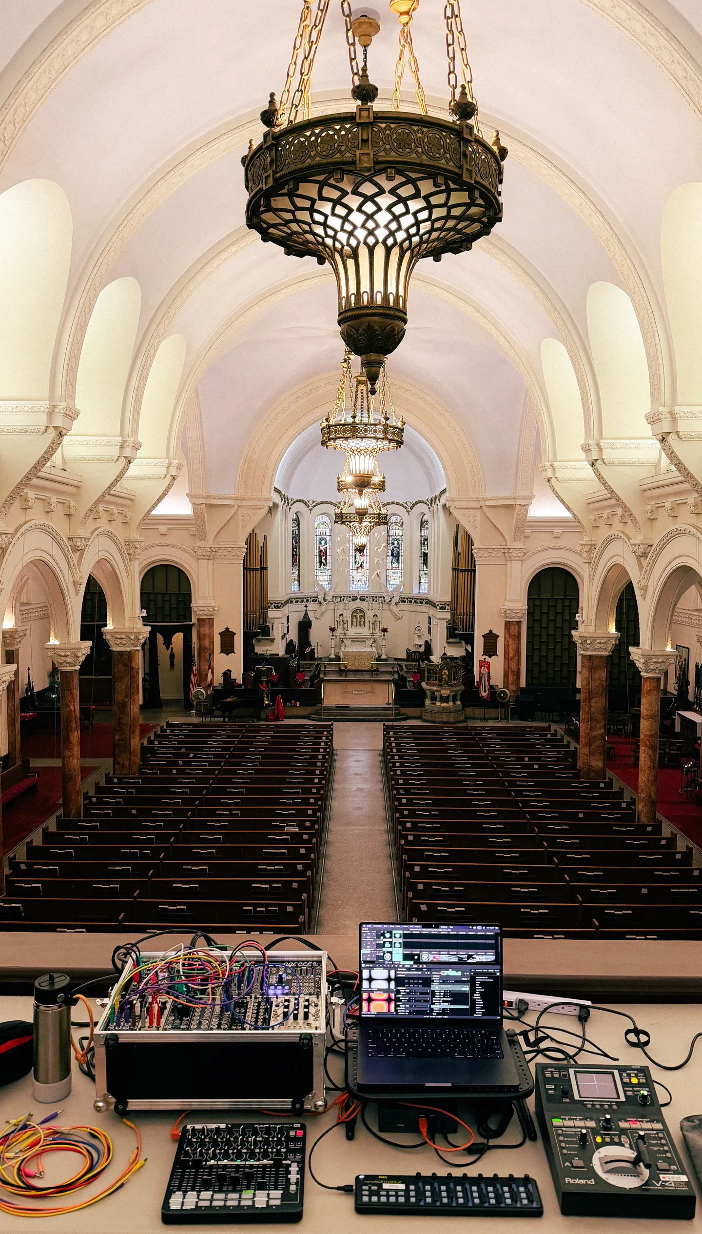 The interior of a large church with a modular synth and digital video equipment on the back balcony
