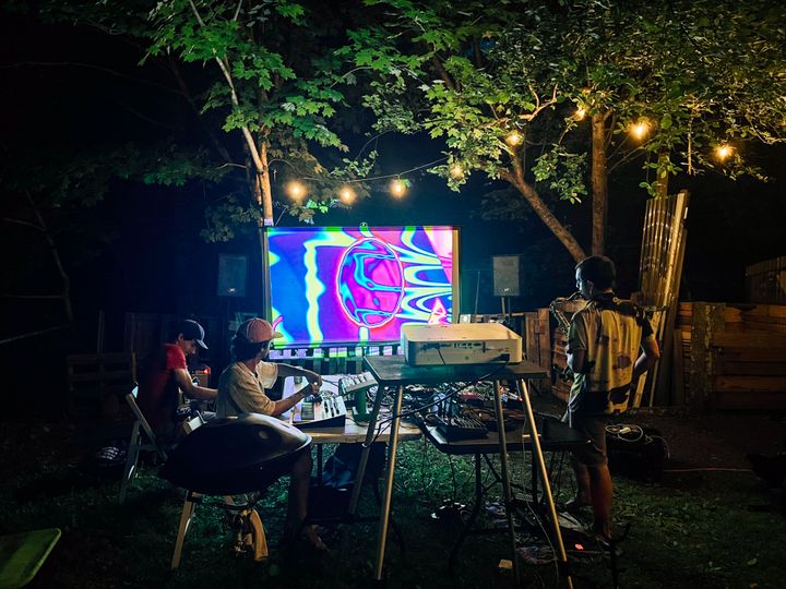 Audiovisual jams at night under a tree strung with lights