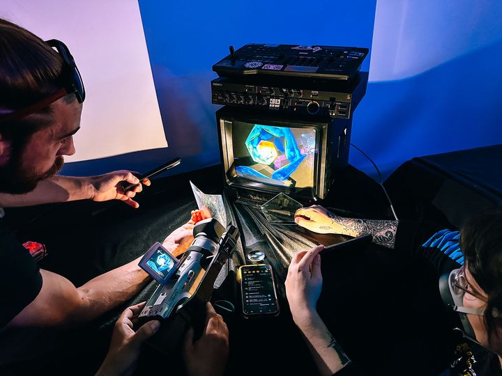 Three people around a TV doing video feedback