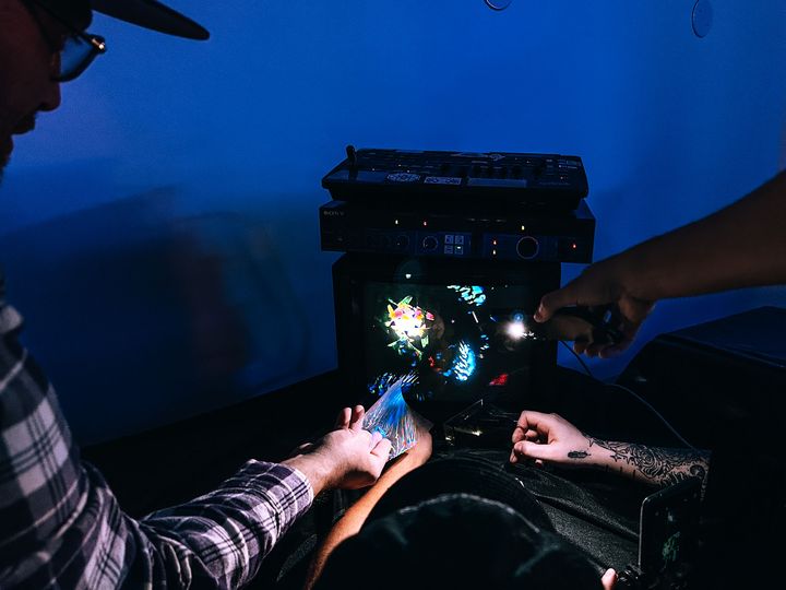 Three people standing around a TV manipulating video feedback