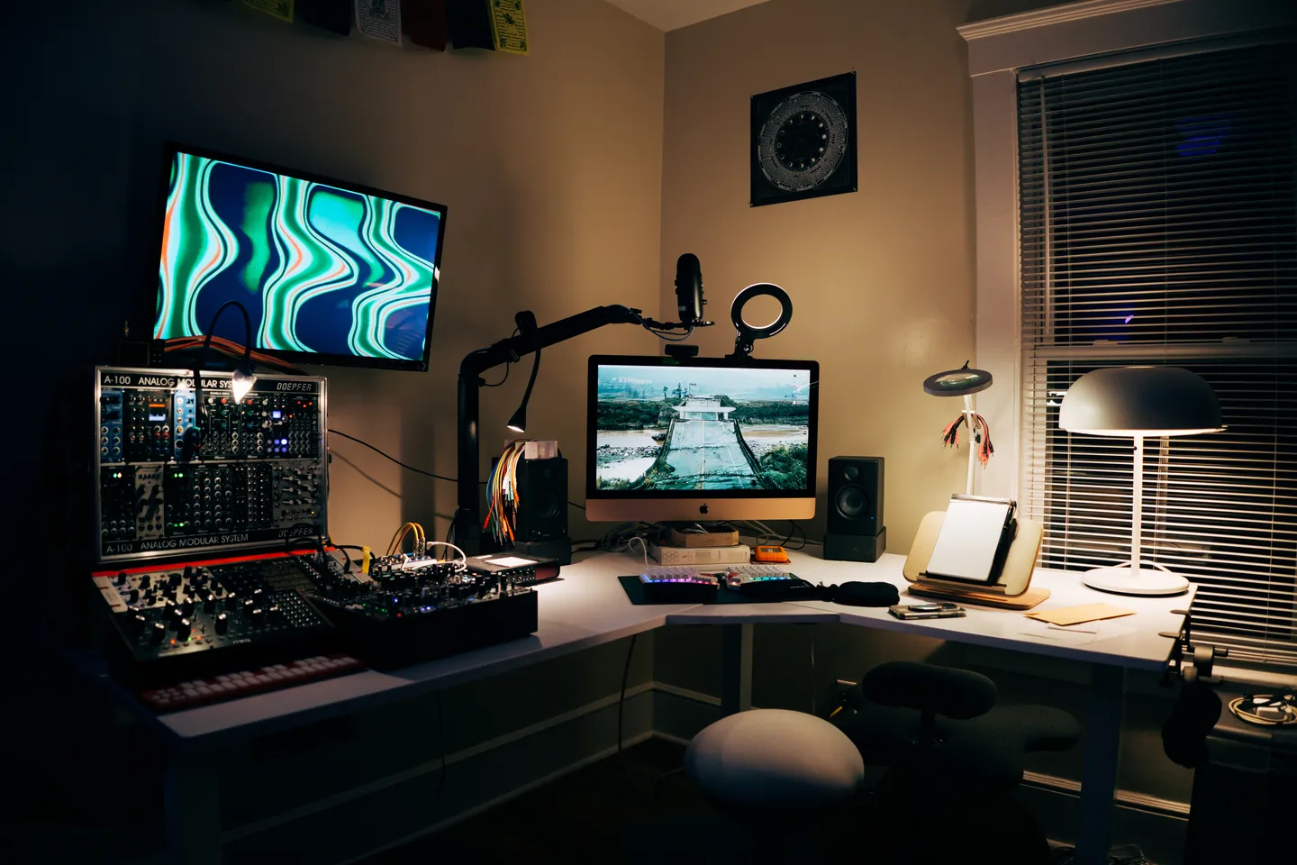 Work desk with a computer and modular synthesizer in a darkened room